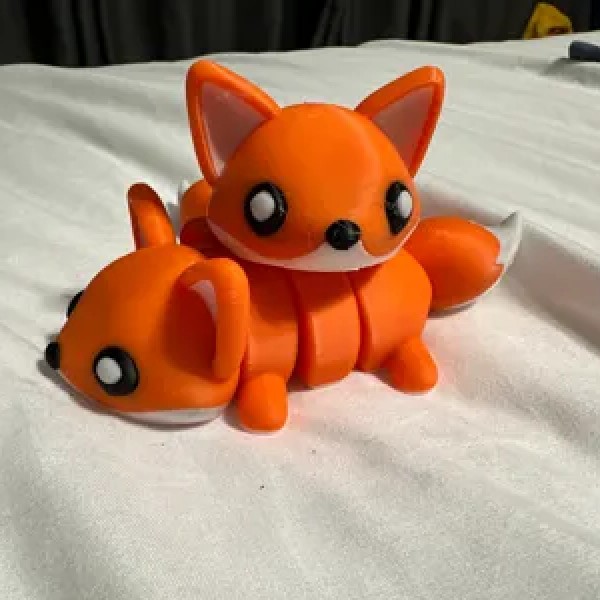 Turuncu, sevimli yüz ifadeli ve eklemli gövdeli tilki figürü.